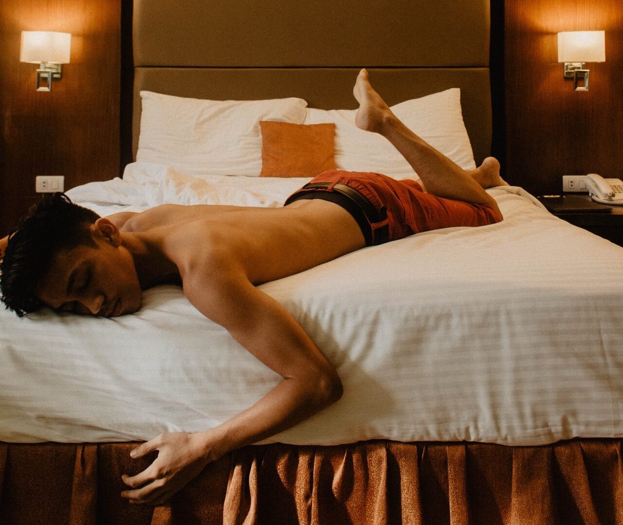 Shirtless man laying on bed with closed eyes