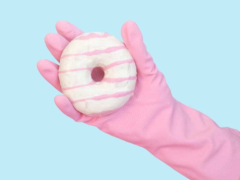 Pink rubber glove holding pink and white donut