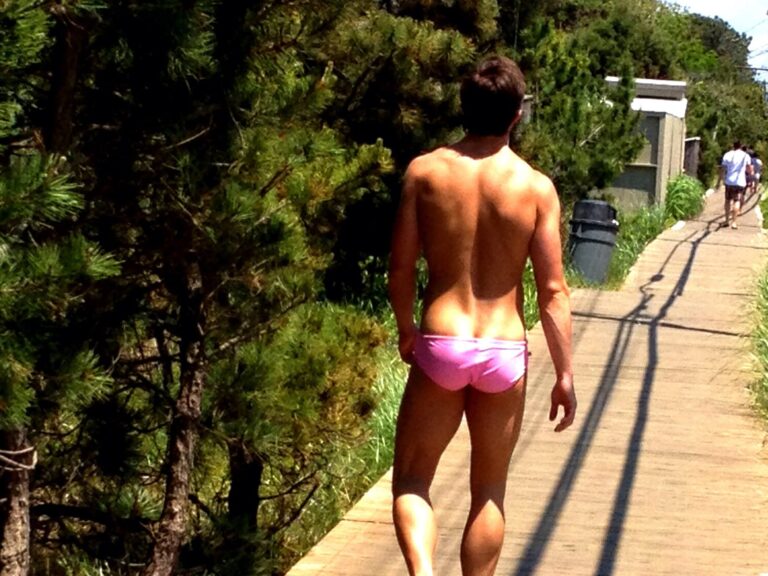 Back of man in bikini strutting on the Fire Island Pines boardwalk