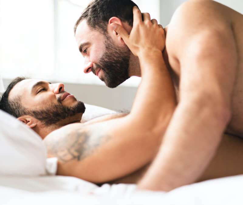 Naked gay couple embracing in bed