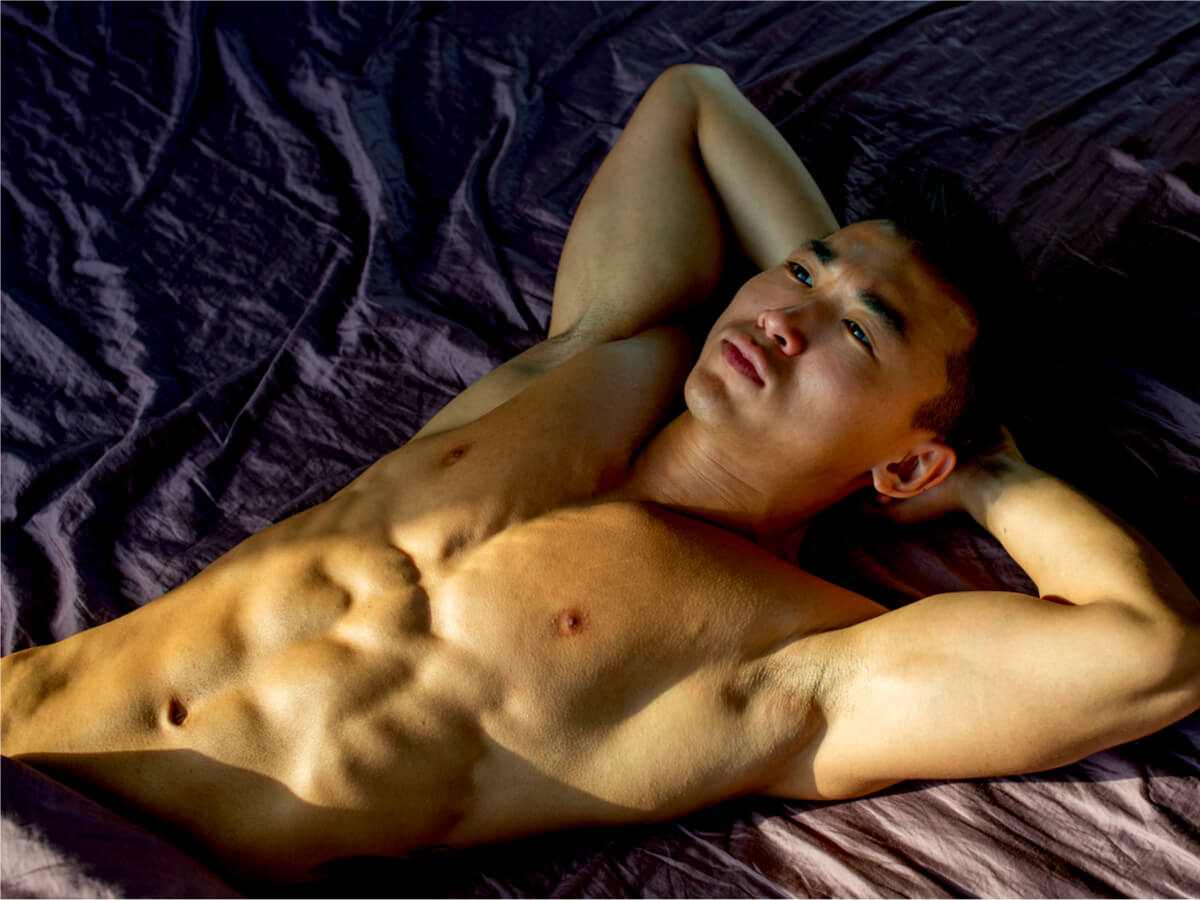 Muscled shirtless man lying on bed