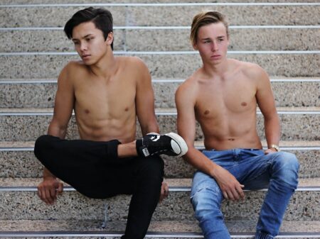 Two shirtless young men sitting on stairs