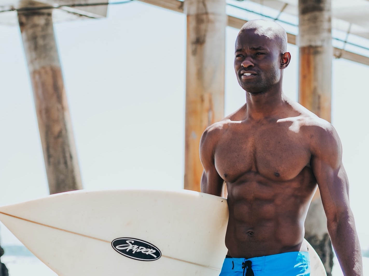 Shirtless surfer carrying surfboard